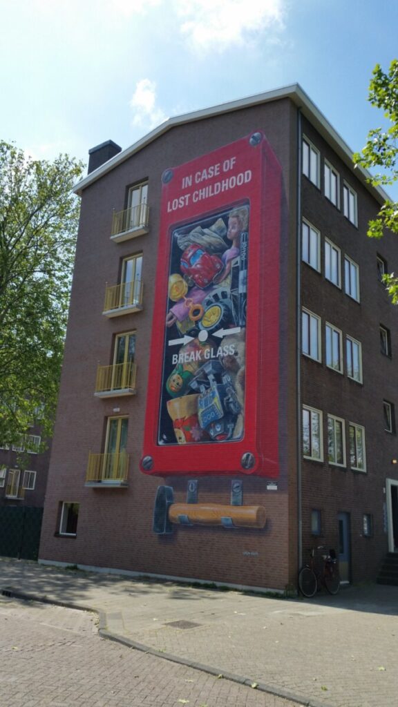 Mural titled "In Case of Lost Childhood, Break Glass" by Leon Keer, featuring vibrant colors and whimsical childhood imagery.