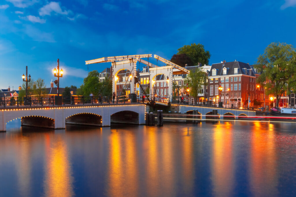 Panoramic view of the Magere Brug Bridge with lights at night by the river Amstel in Amsterdam, Netherlands