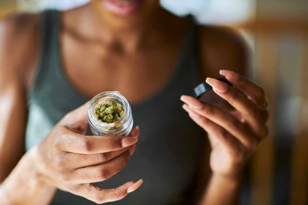 Woman holding a bottle with marijuana drug inside