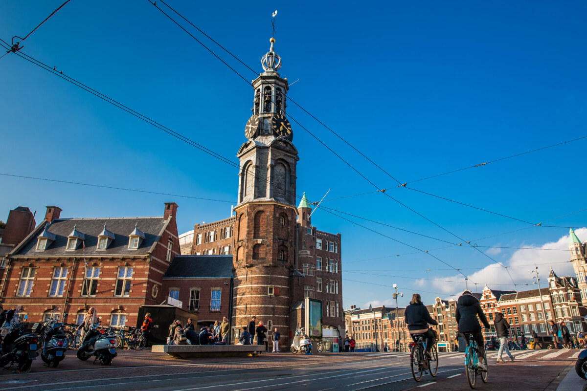 People walking and biking near the Mint Tower at Muntplein Square in Amsterdam, Netherlands