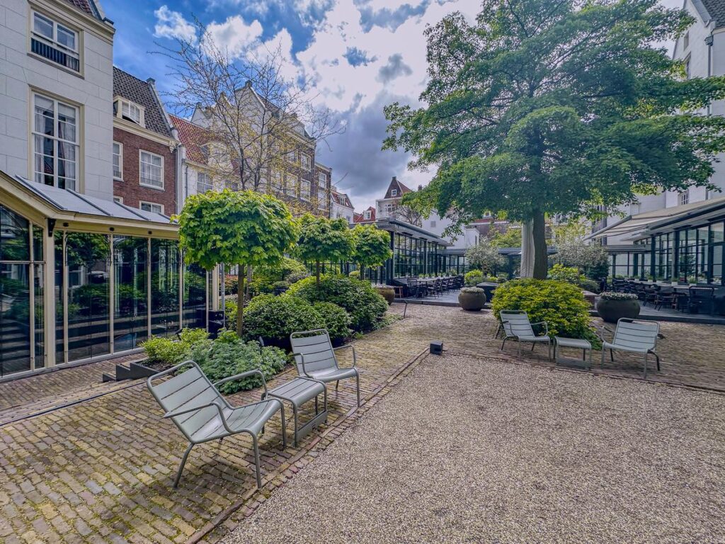 Tranquil courtyard oasis at Pulitzer Hotel, Amsterdam: A serene urban garden with lush greenery and elegant seating.