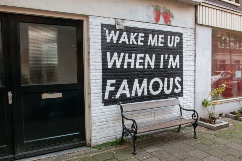 Street painting of the "Wake me up when I'm famous" logo in De Pijp, Amsterdam, showcasing vibrant colors and urban art